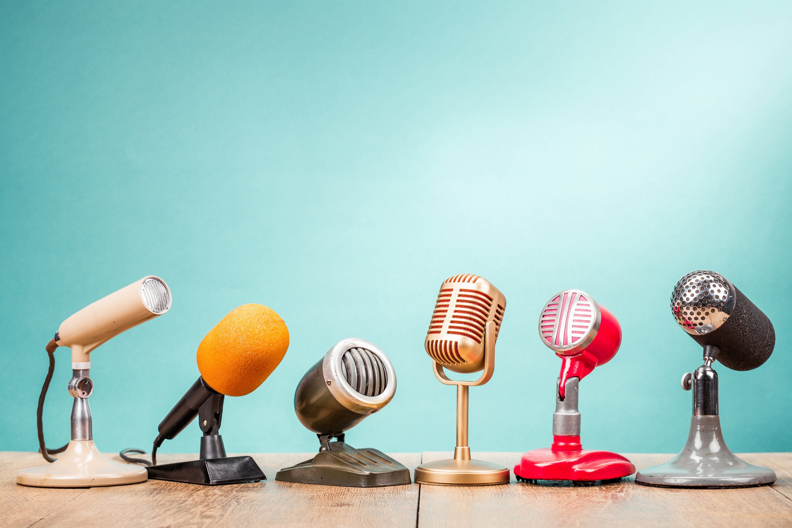 Retro old microphones for press conference or interview on table front gradient aquamarine background. Vintage old style filtered photo